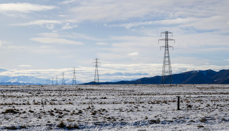 Power pylon and power lines on snow-covered field in winter. Twizel. South Island. New Zealand.