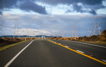 Power pylons and power lines on both sides of the Desert Road. Truck driving on the road. North Island. New Zealand.の写真素材
