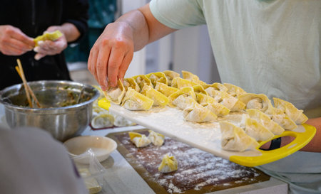 Hands of people making wontons on the kitchen table.の写真素材