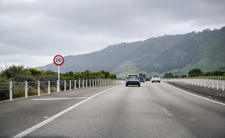 110 km/h speed limit sign at Kapiti Expressway. Cars travelling on the expressway under a cloudy sky. New Zealand;の写真素材