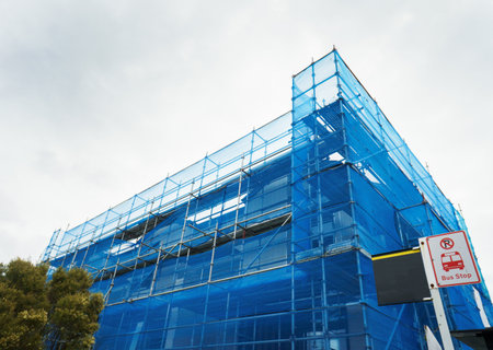 Residential apartment building under construction covered in blue mesh tarp. Auckland.の写真素材