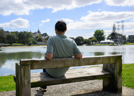 Man sitting on the bench by the lagoon. Onehunga Bay Reserve. Auckland.