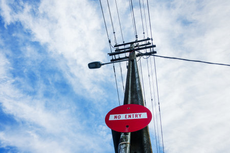 Low angle view of power post and power lines. No Entry road sign on the post. Auckland.の写真素材