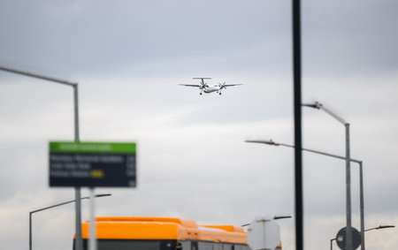 Airplane flying over street lamp posts and bus. Auckland.の写真素材