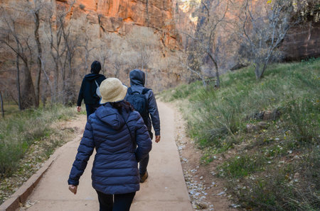 Tourists walking at the foot of steep red cliffs. Zion National Park. Utah. USA.の写真素材