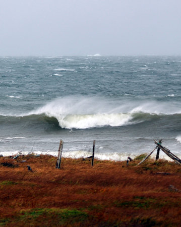 An old fence and rough sea with waves rolling in