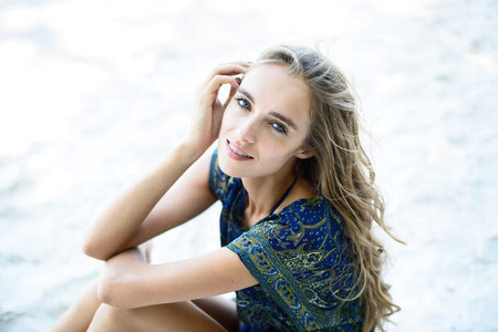 Beautiful woman sitting on the white beach sandの写真素材