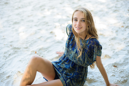 Beautiful woman sitting on the white beach sandの写真素材