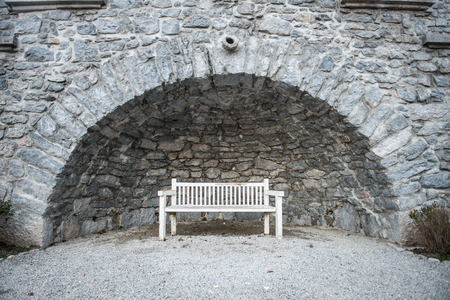 Empty white park bench under stone bridgeの写真素材