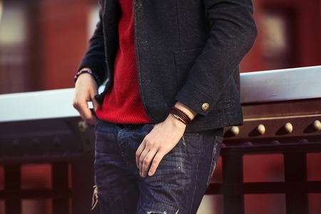 Men casual street style clothes with jeans, jacket, red pullover and wristbandの写真素材