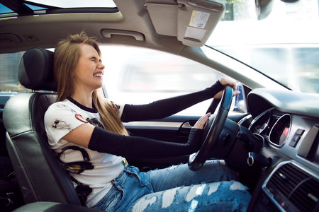 Beautiful blonde woman beep in the car in panic with closed eyes while driving on high speed.