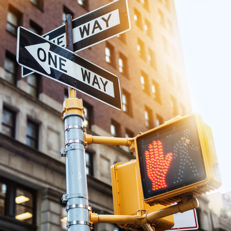 New York City road sign One Way with traffic pedestrian light on the street under sunset light. Urban city lifestyle photo.の写真素材