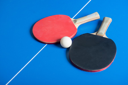 Pin pong ball with red paddle on blue boardの写真素材