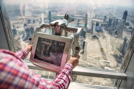 Woman using tourist digital binoculars in dubai skyscraper