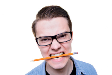 Angry man student holding pencil in the teethの写真素材