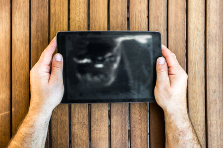 Man holding tablet pc in hands on wooden backgroundの写真素材