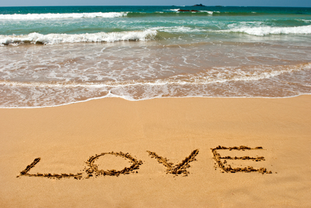 inscription "LOVE" on wet golden beach sandの写真素材