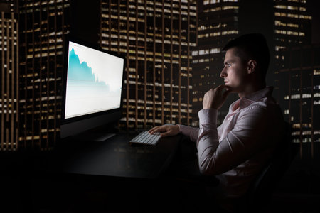 Stock trader checking oil quotes on stock exchange market during night trading in the office in New...