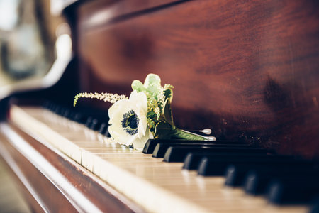 Wedding day concept. Boutonniere flower for groom on the vintage piano keys.