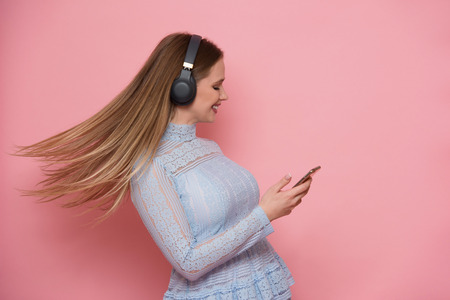 Beautiful happy young woman listen music and usung mobile application isolated on whiteの写真素材