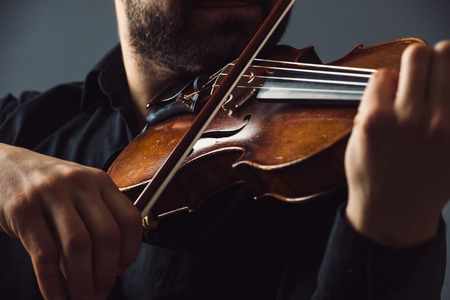 Close-up photo of musician man playing the violin. Musical instrument on performer hands. Classic music concept.の写真素材