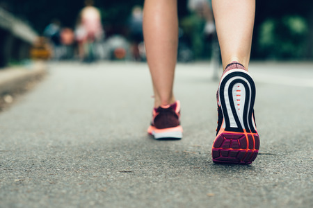Woman feet closeu-up wearing sneakers during marathon run on asphalt city roadの写真素材
