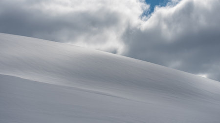 Dramatic clouds coming in from behind snowy mountainside to block the sky in arctic Svalbardの写真素材