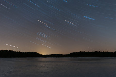 A long exposure of frozen lake after sunset with star trails in the forests of Pirkanmaa, Finland