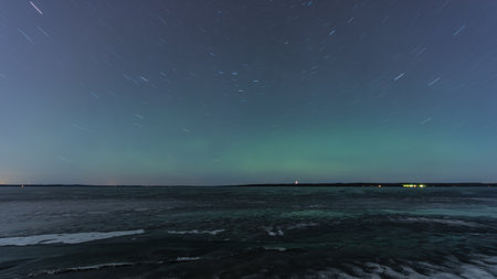 Green aurora borealis hue and rotating stars over a frozen lake in Tampere, Finlandの写真素材