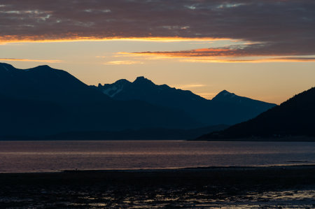 Clouds colored by sunset over mountains and a fjord in northern Norwayの写真素材