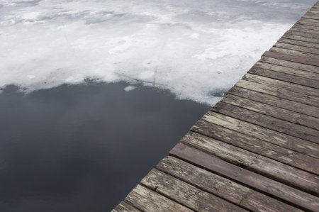 Melting lake ice in spring with a part of a wooden jetty showing in the cornerの写真素材