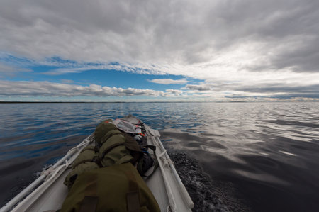 Driving a small inflatable boat on a large lake in Finnish Lapland in summer in Inari, Lapland, Finlandの写真素材