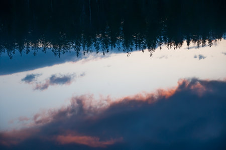 Clouds and forests reflected on the surface of a calm lake in Finlandの写真素材