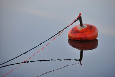 A lonely, red buoy in calm sea in summer in Finlandの写真素材