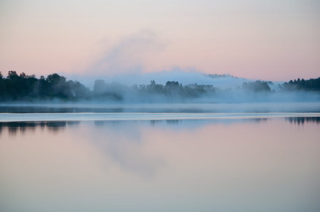 Early summer night by a calm lake in Finland with fog rising from the waterの写真素材