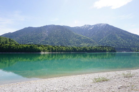 Very blue lake in the mountains of Bavaria in Germany with forrestの写真素材