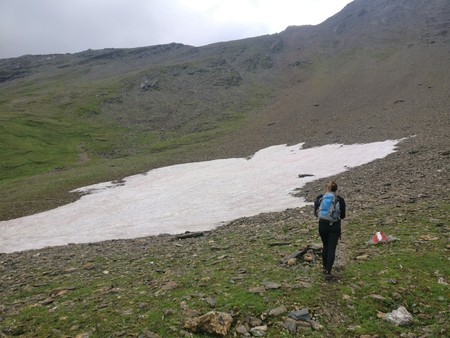 Hiker girl walking on a stone and snow field in the mountains with backpackのeditorial素材