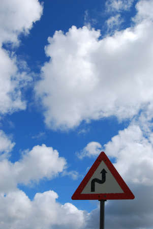 Roadsign.Warning,winding road ahead.As life can also be a winding road.Nice sky in the background.Space for text.の写真素材