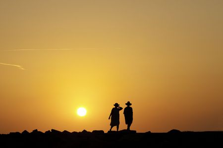 A man and a woman walking at sunset.の写真素材