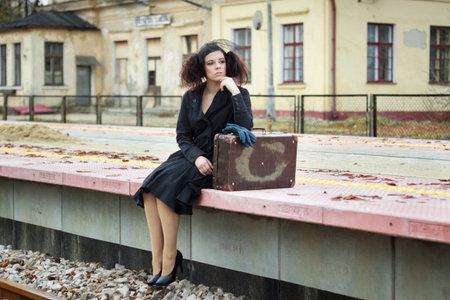 Girl waiting for train on empty railroad platform