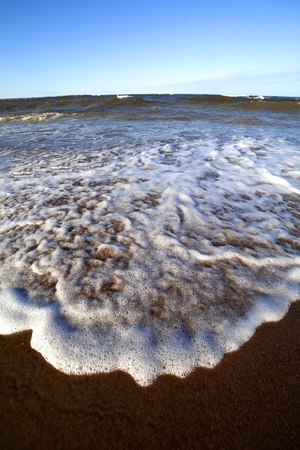 Foamy sea waves on the beach sand の写真素材