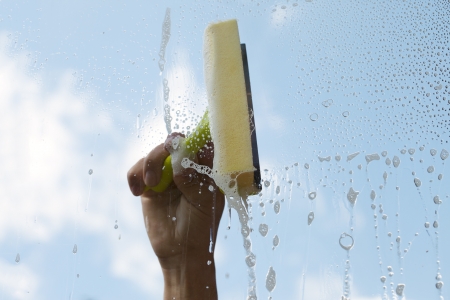 Hand cleaning window against blue sky の写真素材