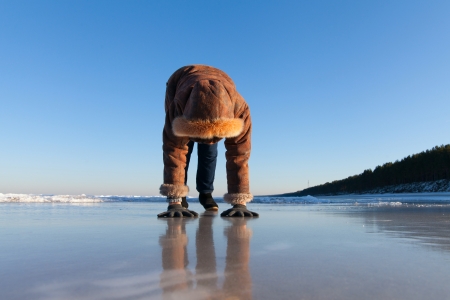 Woman on very slippery ice at sea coast の写真素材