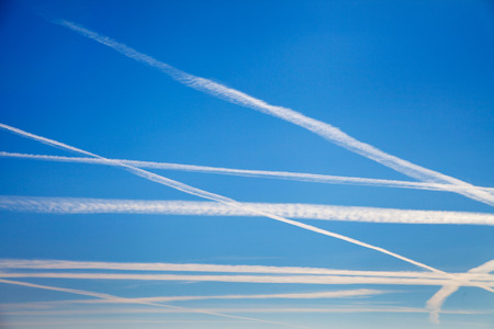 Plane trails in blue sky.の写真素材