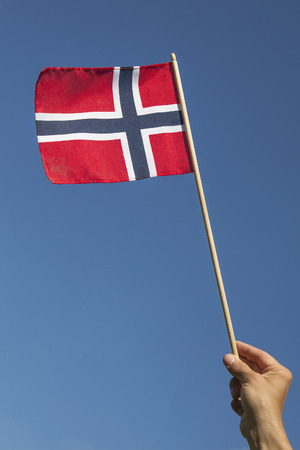 Norwegian flag in hand against blue sky.の写真素材