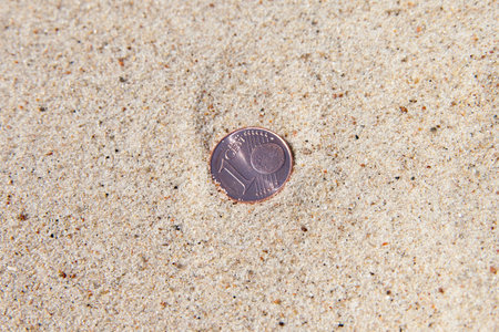 Euro coin in dry sand.