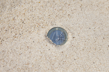 Euro coin in dry sand.の写真素材