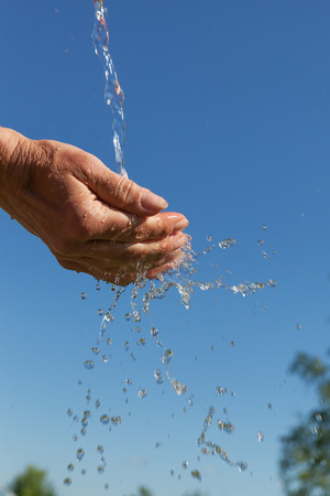 Splashing  water and hands against summer sky.の写真素材