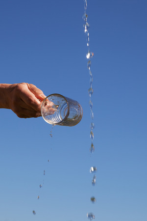 Splashing water and glass against summer sky.の写真素材