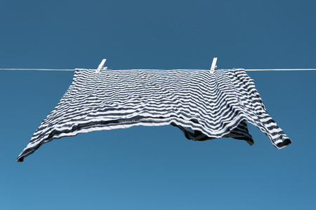 Shirt drying on clothesline against blue sky.の写真素材